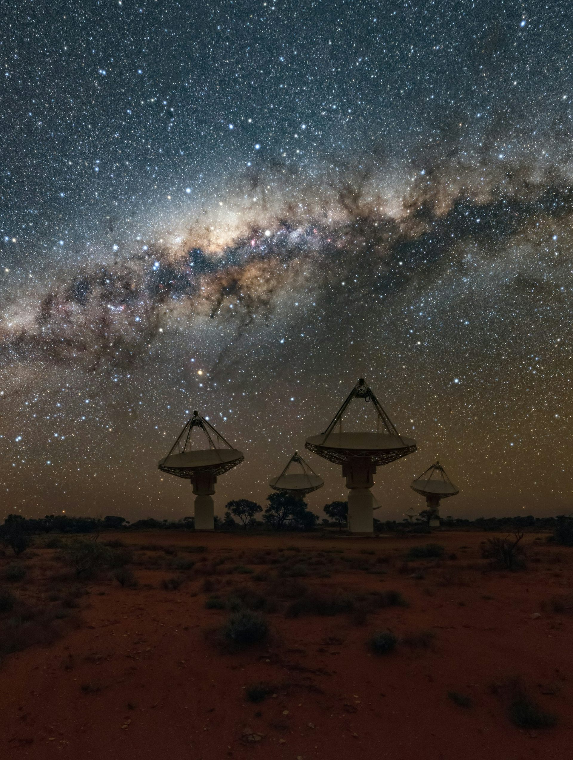 Four dishes of the ASKAP radio telescope in the Western Australian outback under a vivid Milky Way.