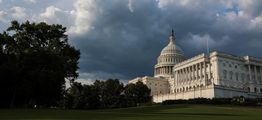 The U.S. Capitol building seen from the National Mall under a darkening sky.