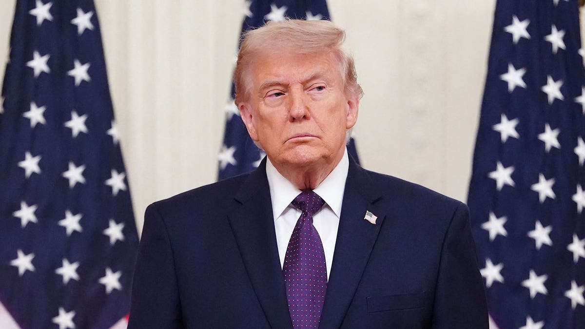 President Donald Trump standing between two American flags at a White House event.