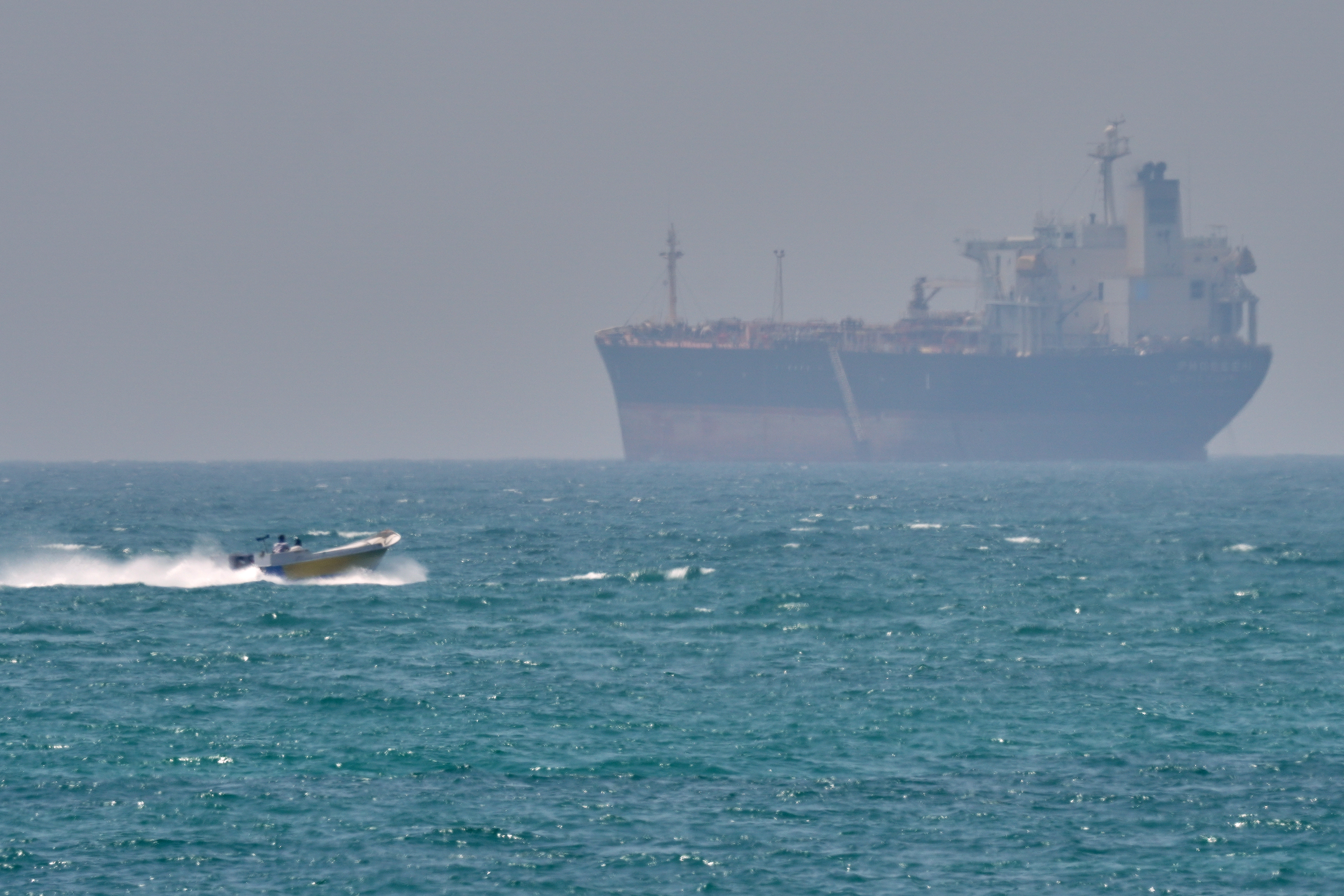 An Iranian Revolutionary Guard Corps speedboat passes a tanker in the Strait of Hormuz near Qeshm Island.