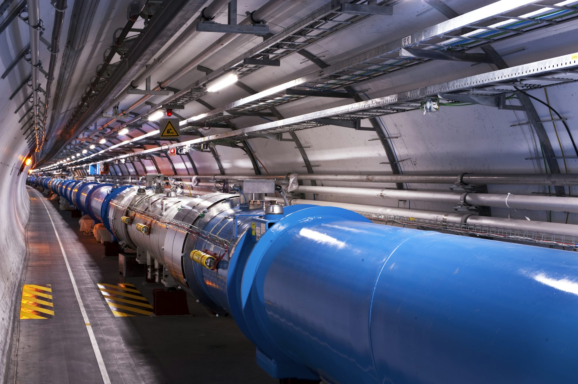 A view inside the LHC tunnel at CERN, showing the blue dipole magnets that bend the proton beam.