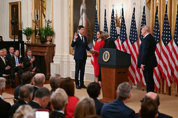 Kevin Warsh raises his right hand as Justice Clarence Thomas administers the oath of office in the White House East Room while President Trump looks on.