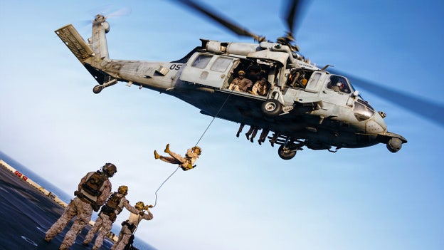 US Navy special operators rappel from an MH-60S helicopter onto the deck of USS Tripoli in the Gulf.